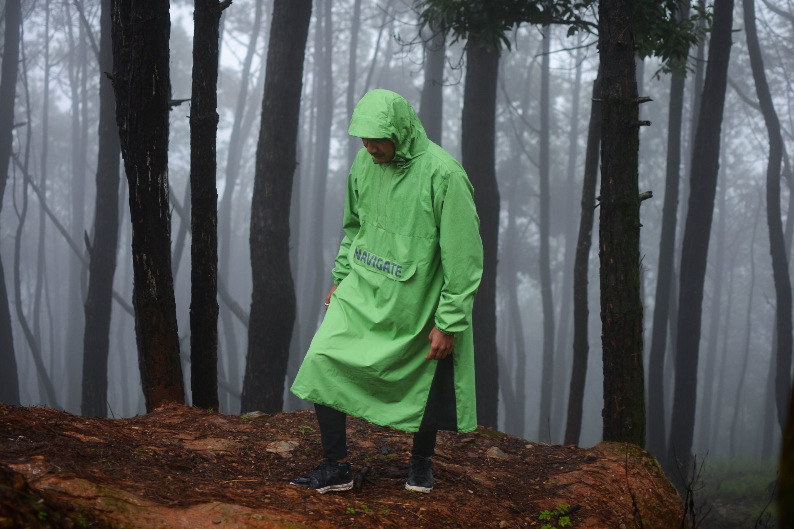 A man wearing navigate raincoat in foggy rain forest